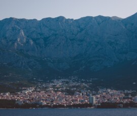 Strona główna A breathtaking view of Makarska city nestled against a majestic mountain range by the sea.